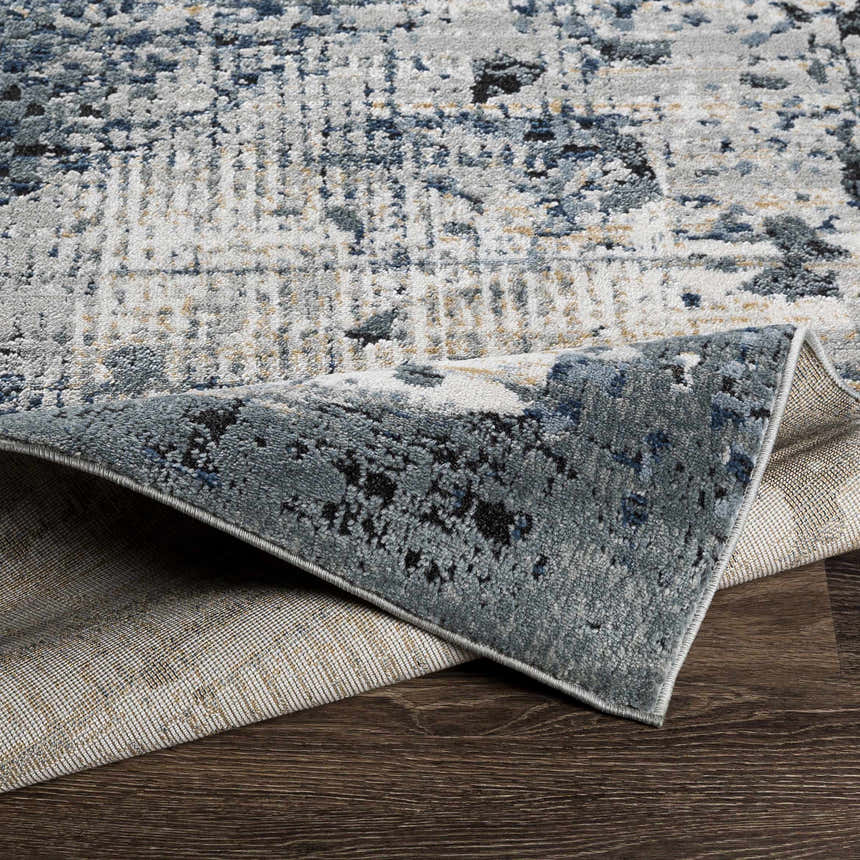 Close-up of the Waterboro Area Rug showing its black, charcoal, and blue contemporary pattern and woven texture. Fold