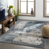 Living room scene with a blue and gray Waterboro Area Rug, wood bench, and natural light from windows. Roomscene-Rectangle