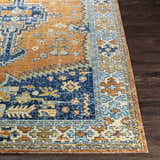 Close-up of the Trotters Orange/Blue Performance Rug showing its traditional, bohemian pattern and brick red, navy, and saffron colors. Front