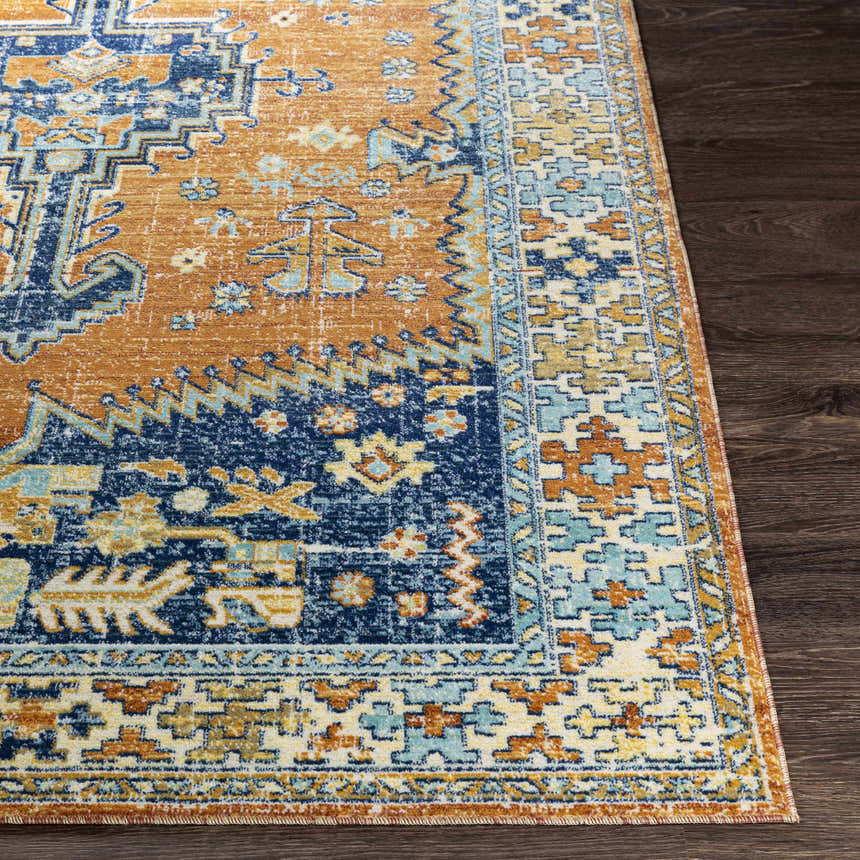 Close-up of the Trotters Orange/Blue Performance Rug showing its traditional, bohemian pattern and brick red, navy, and saffron colors. Front