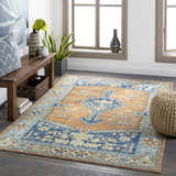 Living room scene with Trotters Orange/Blue Performance Rug, wood bench, woven pouf, and natural light. Bohemian style. Roomscene-Rectangle
