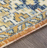 Close-up of the Trotters Orange/Blue Performance Rug showing its intricate bohemian pattern and colors on a dark wood floor. Texture