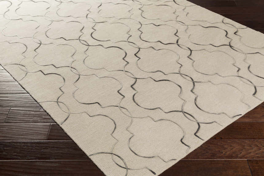 Close-up of the Wycombe Area Carpet Area Rug. Taupe wool rug with a black geometric trellis pattern on dark wood floors. Corner