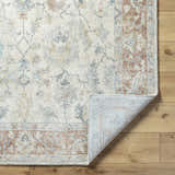 Close-up of the Yetta Beige Thick Luxe Area Rug showing its traditional floral pattern and colors on a wood floor. Fold