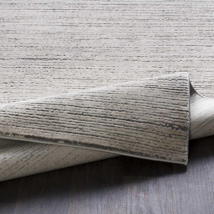 Close-up of the textured Yemassee Tibetan Striped Area Rug in charcoal, ivory, and gray. Machine woven rug detail. Fold