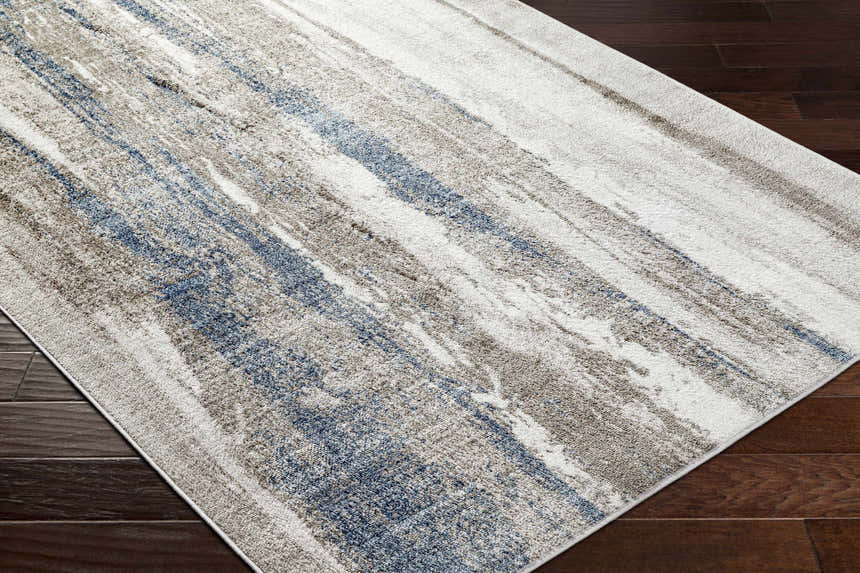 Close-up of the Yuina Light Gray Area Rug showing its blue, gray, and cream abstract design on dark wood floors. Corner