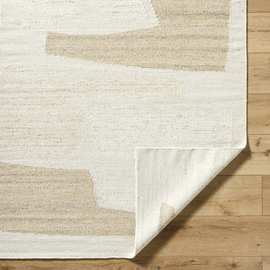Close-up of the hand-woven Airell Area Rug showing a geometric pattern in pearl and brick red on a wood floor. Fold