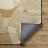 Close-up of the Yaxha Modern Wool Rug showing its camel, tan, and warm gray geometric pattern and hand-tufted texture. Fold