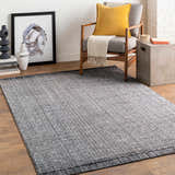 Living room scene with a hand loomed light gray area rug, gray chair, and modern decor. Roomscene-Rectangle