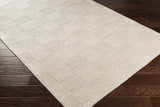 Close up of the hand woven Yarrabilba Area Rug in off white with a subtle geometric pattern on dark wood floors. Corner