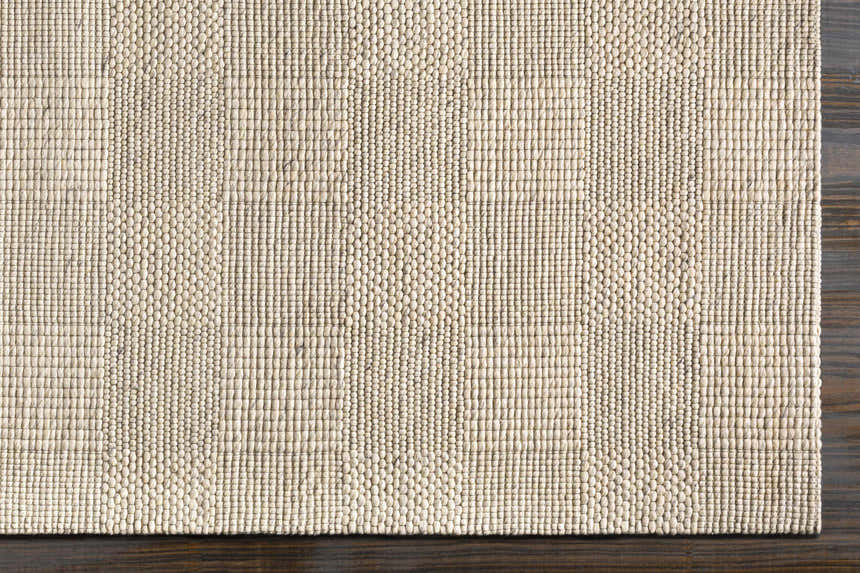 Close-up of the hand woven Yarrabilba Area Rug. Off white rug with a textured, contemporary design. Corner