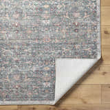 Close-up of the Zilya Area Rug featuring a traditional floral pattern in dark brown, green, peach, and rust hues. Fold