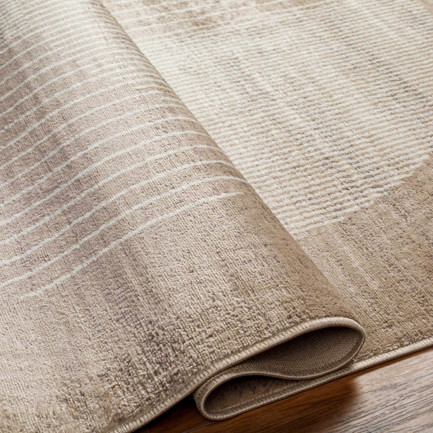 Close-up of the Zeke Area Rug showing bone and mocha colors and a subtle geometric pattern. Fold