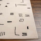 Close up of the Zale Area Rug showing a bone color with a dark gray, geometric pattern. Front