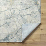 Close-up of the Urowo Light Gray Thick Luxe Rug showing its cream, gray, and light blue contemporary design and texture. Fold