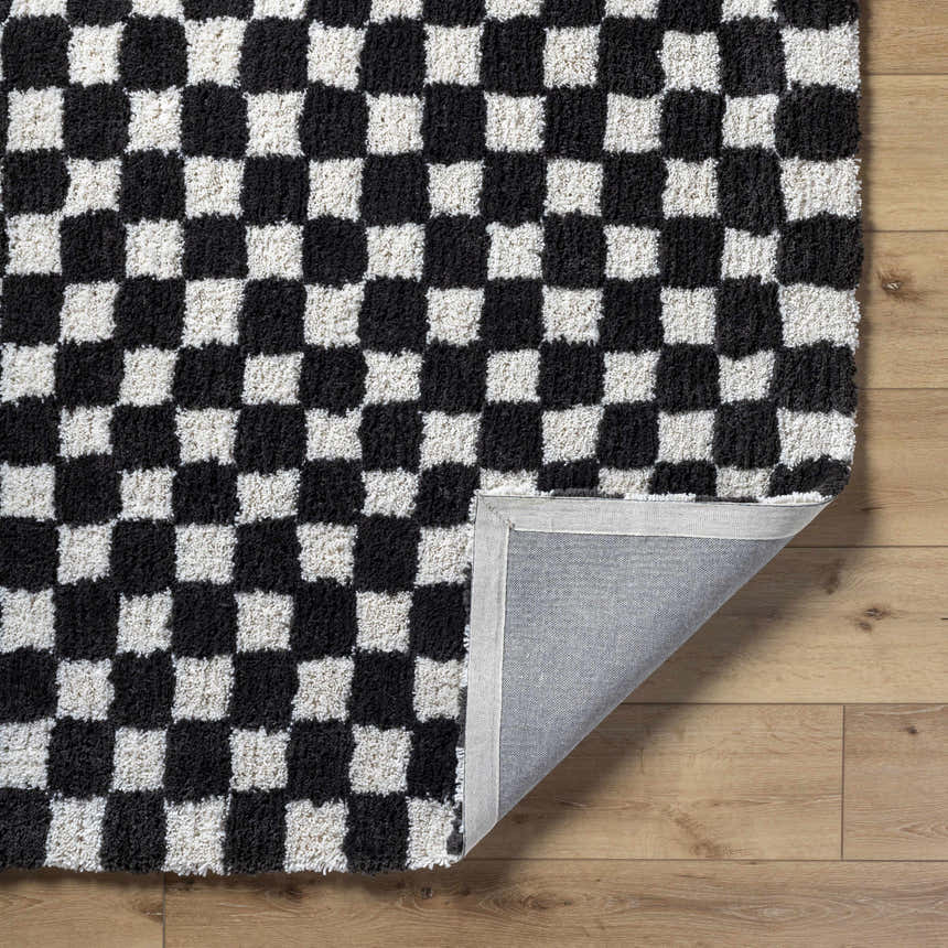 Close-up of the Zveha Area Rug. Black and light silver checkerboard pattern, hand-tufted microfiber texture. Fold