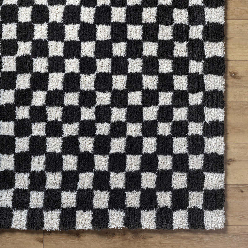 Close-up of the Zveha Area Rug. Black and light silver checkerboard pattern. Hand-tufted microfiber rug. Corner