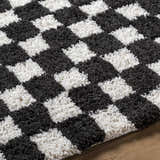 Close-up of the Zveha Area Rug, a hand-tufted microfiber rug with a contemporary black and light silver checkerboard pattern. Texture
